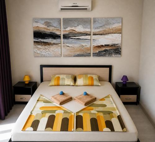 a bedroom with a bed with three paintings on the wall at The White Houses 7 in Nesebar