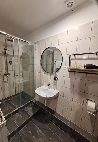 a bathroom with a sink and a shower and a mirror at Mitter-ház Panzió in Zalaszentgrót
