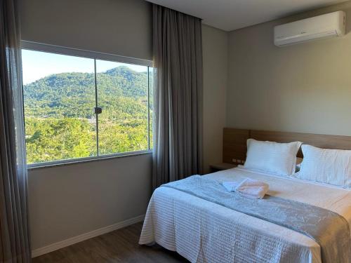 a bedroom with a bed and a large window at Suítes Bela Vista in Pomerode