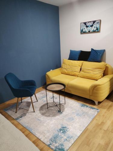 a living room with a yellow couch and a table at Apartman Lanass Doboj in Doboj