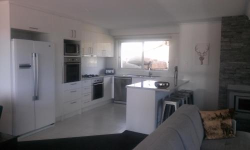 una cucina con armadi bianchi e un divano di Jindabyne Guest House a Jindabyne