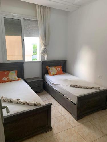 two beds in a room with two windows at Dyar Abdellatif in Kelibia