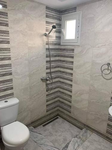 a bathroom with a shower and a toilet and a window at Dyar Abdellatif in Kelibia