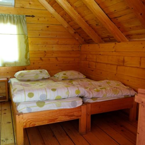 a bed in a wooden room in a cabin at Camp Vrbas in Rekavice