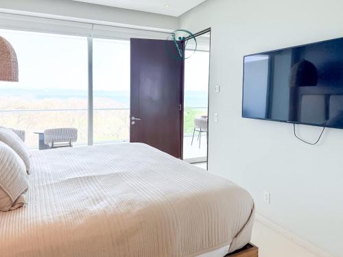 a bedroom with a large bed with a flat screen tv at Endless Ocean Views Luxury Bolongo Escape in Higuera Blanca