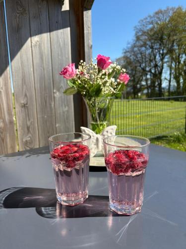 two glasses sitting on a table with a vase of flowers at Ferienwohnung Alpenblick in Wessobrunn