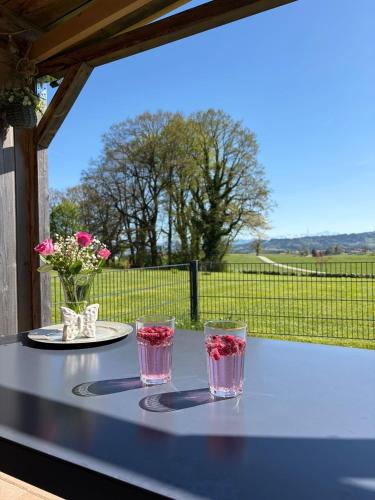 a table with three glasses and a view of a field at Ferienwohnung Alpenblick in Wessobrunn