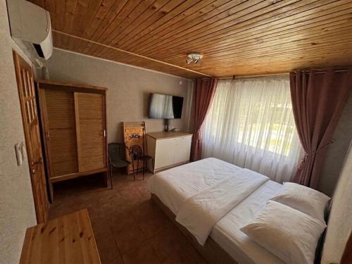 a bedroom with a white bed and a wooden ceiling at okuninkanoclegi in Okuninka