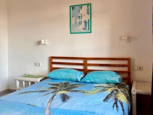 a bedroom with a bed with blue pillows and a palm tree at fuerte blue in Costa Calma