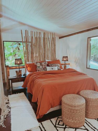 a bedroom with a bed with orange sheets and two lamps at Casa 7 Caraíva No centrinho in Caraíva