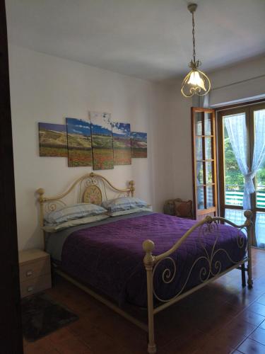 a bedroom with a bed with purple sheets and a chandelier at Appartamento Panoramico in Montepulciano