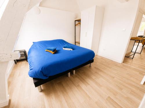 a bed in a room with a blue bedvisor at Loft lumineux & cosy sous les toits in Roubaix