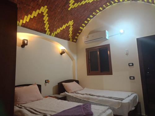 a room with two beds and a ceiling at Manzil Al-Wahati in Bawati