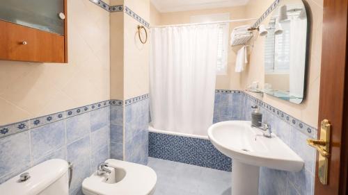 a bathroom with a white toilet and a sink at Hostal Muriel in Aljaraque