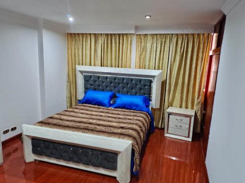 a bedroom with a large bed with blue pillows at Casa cerca al Campín in Bogotá