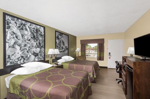 a hotel room with two beds and a flat screen tv at Super 8 by Wyndham Sarasota Near Siesta Key in Sarasota