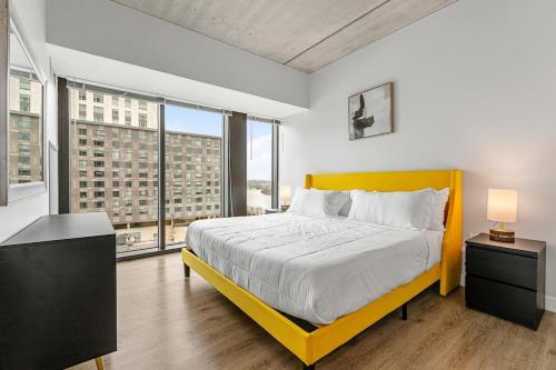 a bedroom with a yellow bed and large windows at High-end Modern 3BR 3BA Condo Assembly Square in Somerville