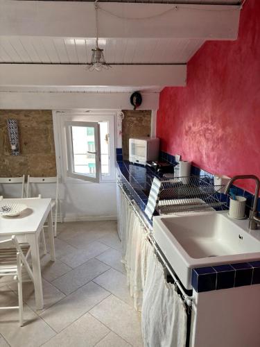 a kitchen with red walls and a white sink at The three bell towers apartment in Alghero