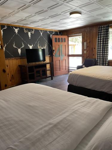 a bedroom with two beds and a flat screen tv at The Spruce Lodge in South Fork