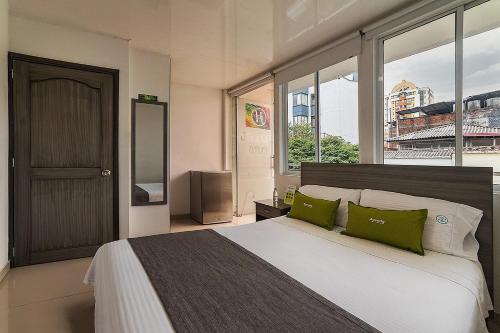 a bedroom with a large bed with green pillows at Hotel Exito La 21 in Pereira