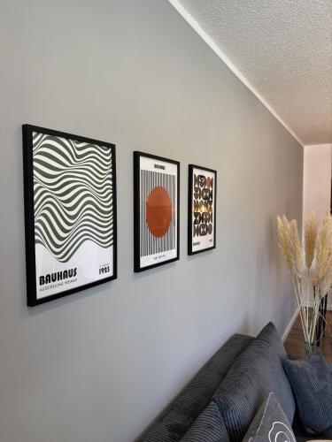 three framed pictures on a white wall with a couch at 100qm Apartment mit Regendusche & Top-Lage in Mücheln