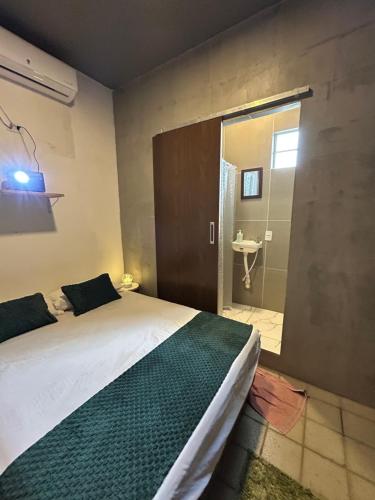 a bedroom with a bed and a bathroom with a sink at Suíte Neblina in Garanhuns