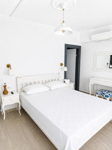a white bedroom with a white bed and two white tables at Hayal Ada in Bozcaada