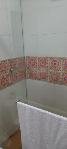 a shower with a glass door and a tile wall at Hostería santa María in Filandia