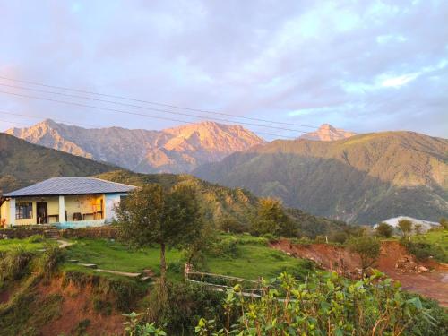 a house on a hill with mountains in the background at peak&valley homestay in Dharmsāla