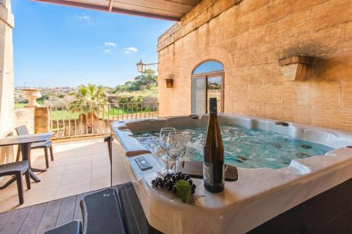 a hot tub with a bottle of wine and glasses at Centre Island Gozitan Farmhouse & Pool - Happy Rentals in Kerċem