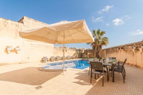 a patio with a table and umbrella next to a pool at Centre Island Gozitan Farmhouse & Pool - Happy Rentals in Kerċem
