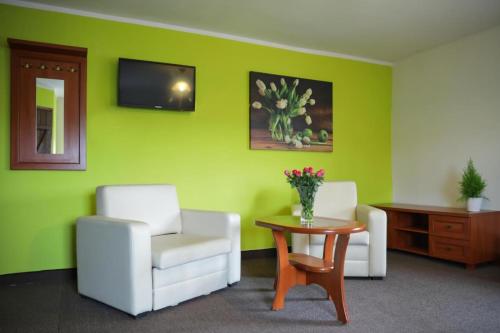 a room with two chairs and a table and a tv at Apartamenty Maciejowy Sad in Sady Dolne