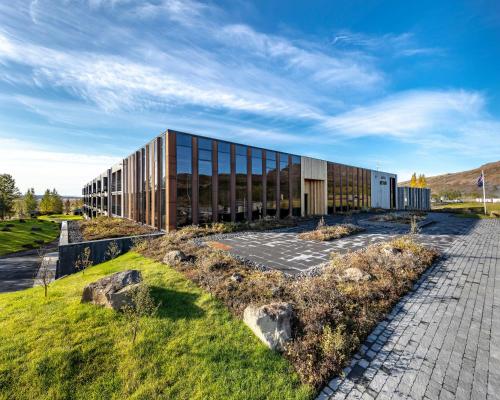 a building on a field with rocks in front of it at Hotel Geysir in Geysir