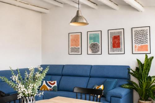 a blue couch in a living room with pictures on the wall at Sésamo Apartamento in Hervás