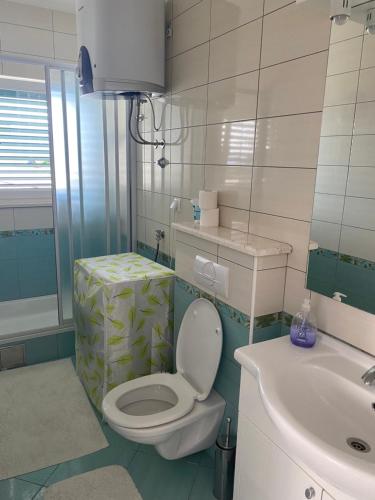 a white bathroom with a toilet and a sink at Beachside 2-Bed Bliss! in Blace