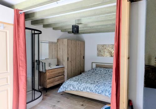 a bedroom with a bed and a wooden dresser at La petite maison de Sandra in Le Plessis-Grohan