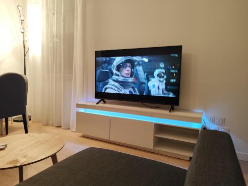 a flat screen tv sitting on a stand in a living room at Chez Mika in Linxe