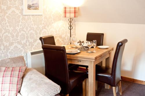 a dining room table with chairs and a lamp at Strathspey Cottage in Carrbridge