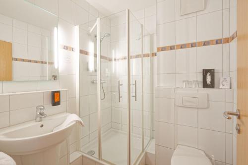 a white bathroom with a shower and a sink at Friends Hotel Kerpen in Kerpen