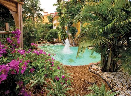 a swimming pool with a fountain in a garden at Sea Gardens Resort Studio Suite in Pompano Beach