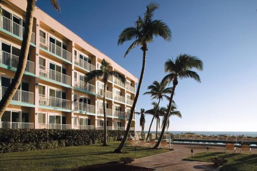 a building with palm trees in front of the ocean at Sea Gardens Resort Studio Suite in Pompano Beach