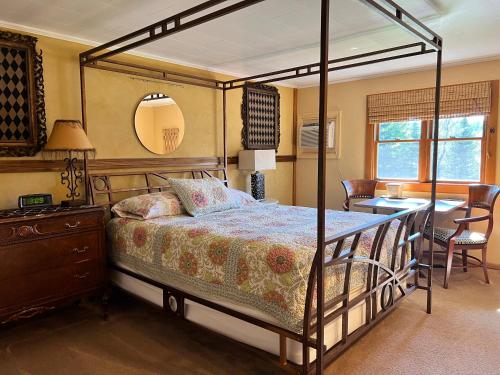 a bedroom with a canopy bed with a table and a kitchen at Barron Brook Inn in Whitefield
