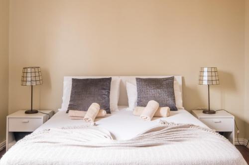 a bedroom with a white bed with two lamps at Ben House, private parking in Ponta Delgada