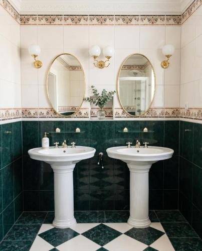 two sinks in a green bathroom with mirrors at Kapitänsapartment in der VILLA KAETHE am Kurpark - moderne & stilvolle 65qm Ferienwohnung nahe Strand in Warnemünde