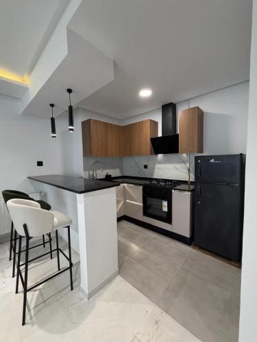 a kitchen with a black refrigerator and a table at Luxueux T2 à Ain Zaghouen in El Aouina