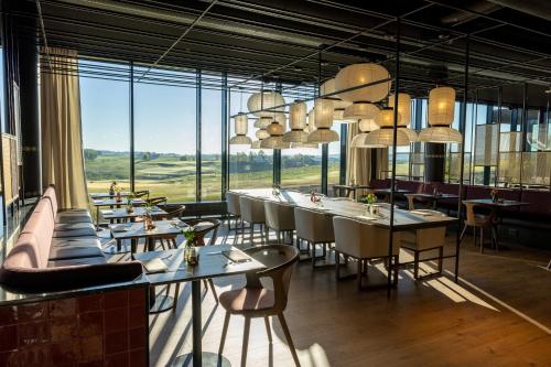 a restaurant with tables and chairs and large windows at Lily Country Club in Klofta
