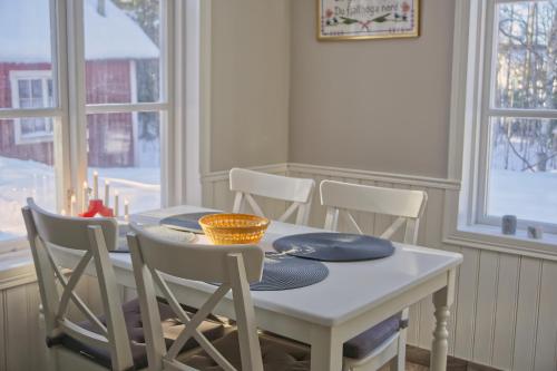 a dining room table with chairs and a white table and windows at Cozy forest cabin in Vik