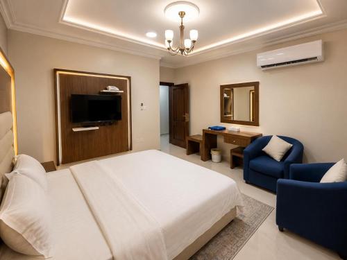 a bedroom with a bed and a chair and a television at تراس للشقق المخدومة in Dammam