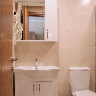 a bathroom with a sink and a toilet and a mirror at Scorpio Hotel Gonio in Gonio