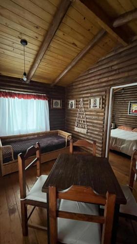 a room with two beds and a table and chairs at Cabañas La Silvanita in Balcarce